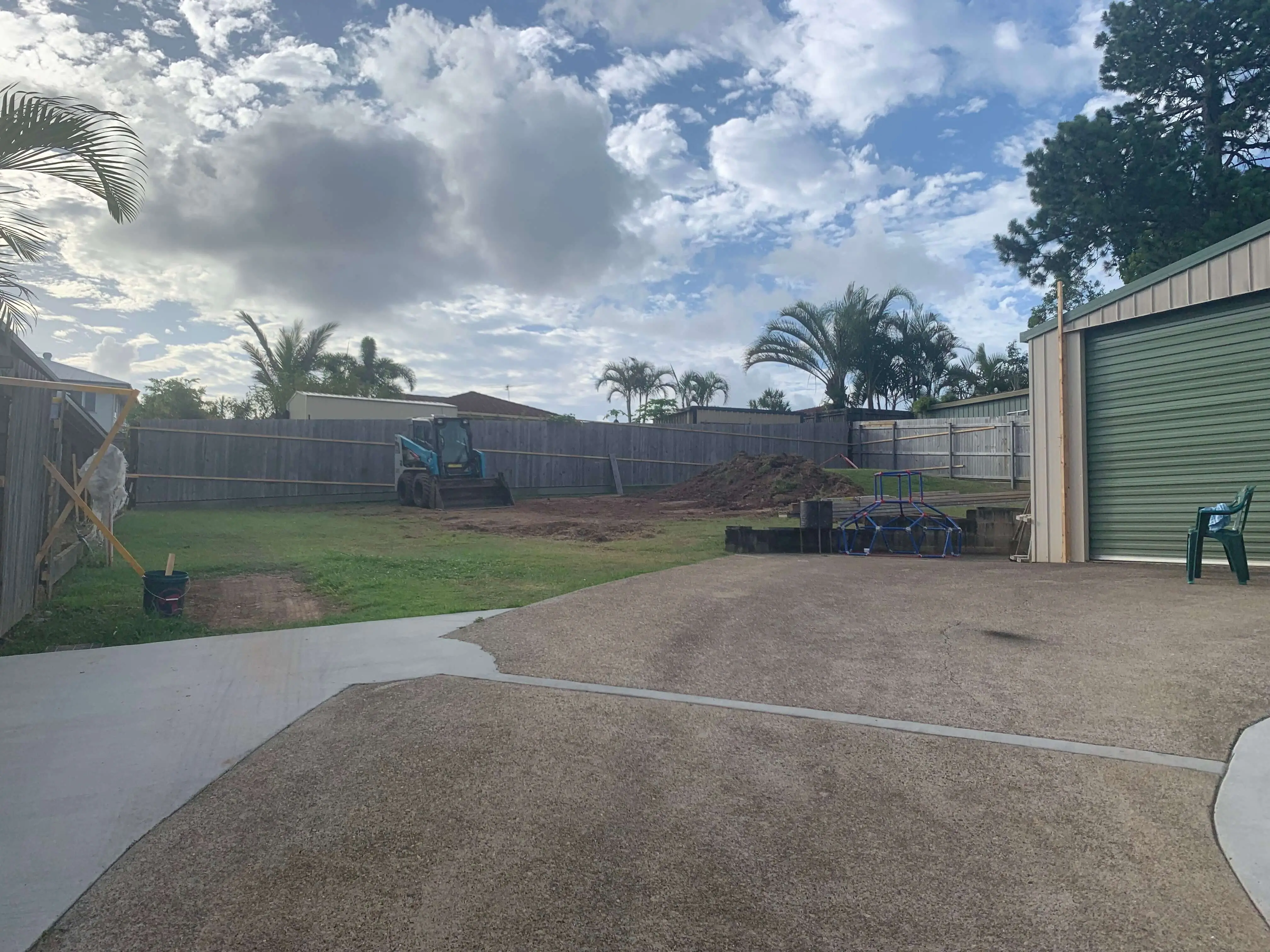 Cleared and levelled backyard with a skid steer working at the rear fence
