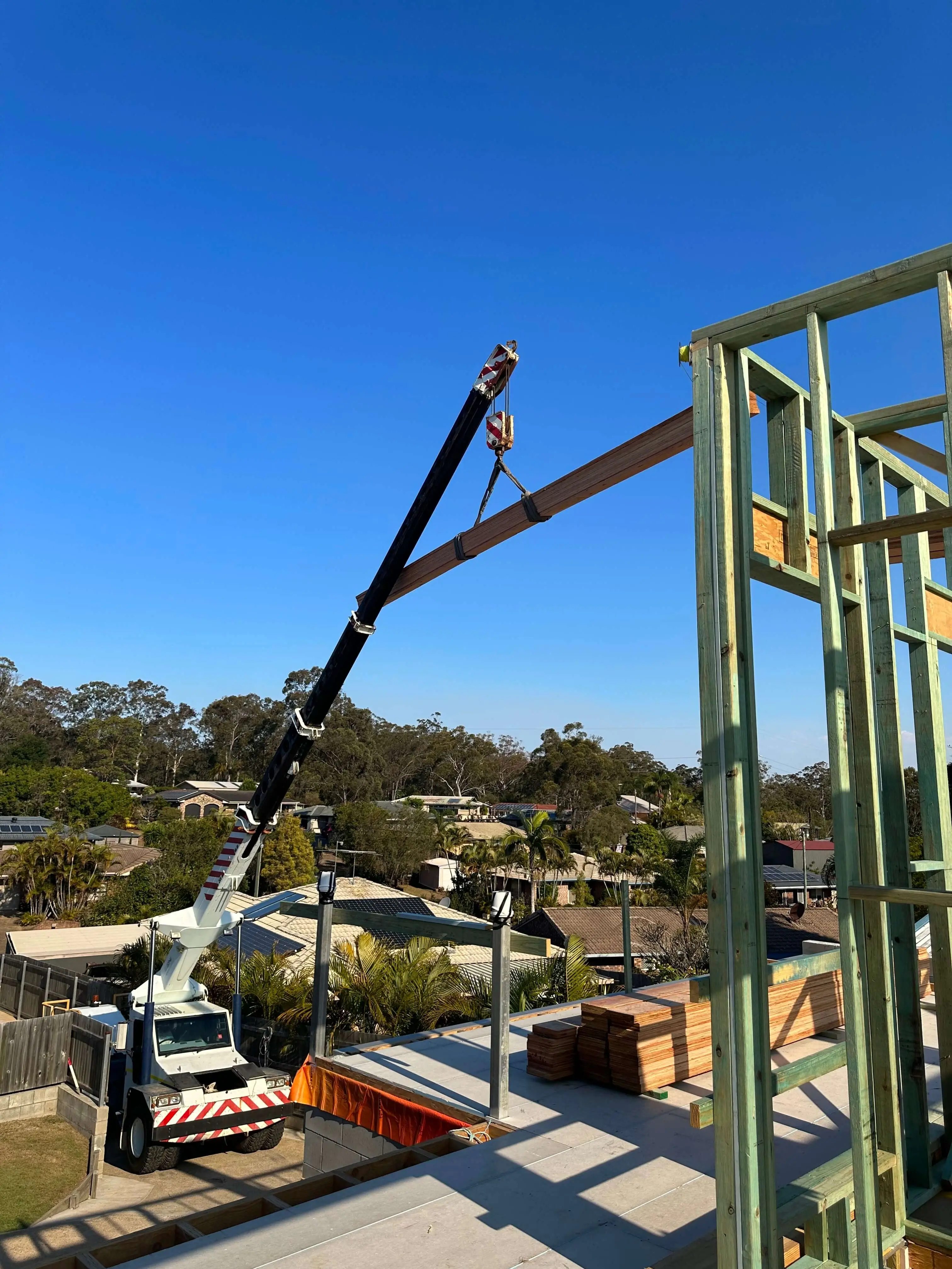 Franna crane lifting an LVL beam onto a new upper-floor wall frame in Brisbane