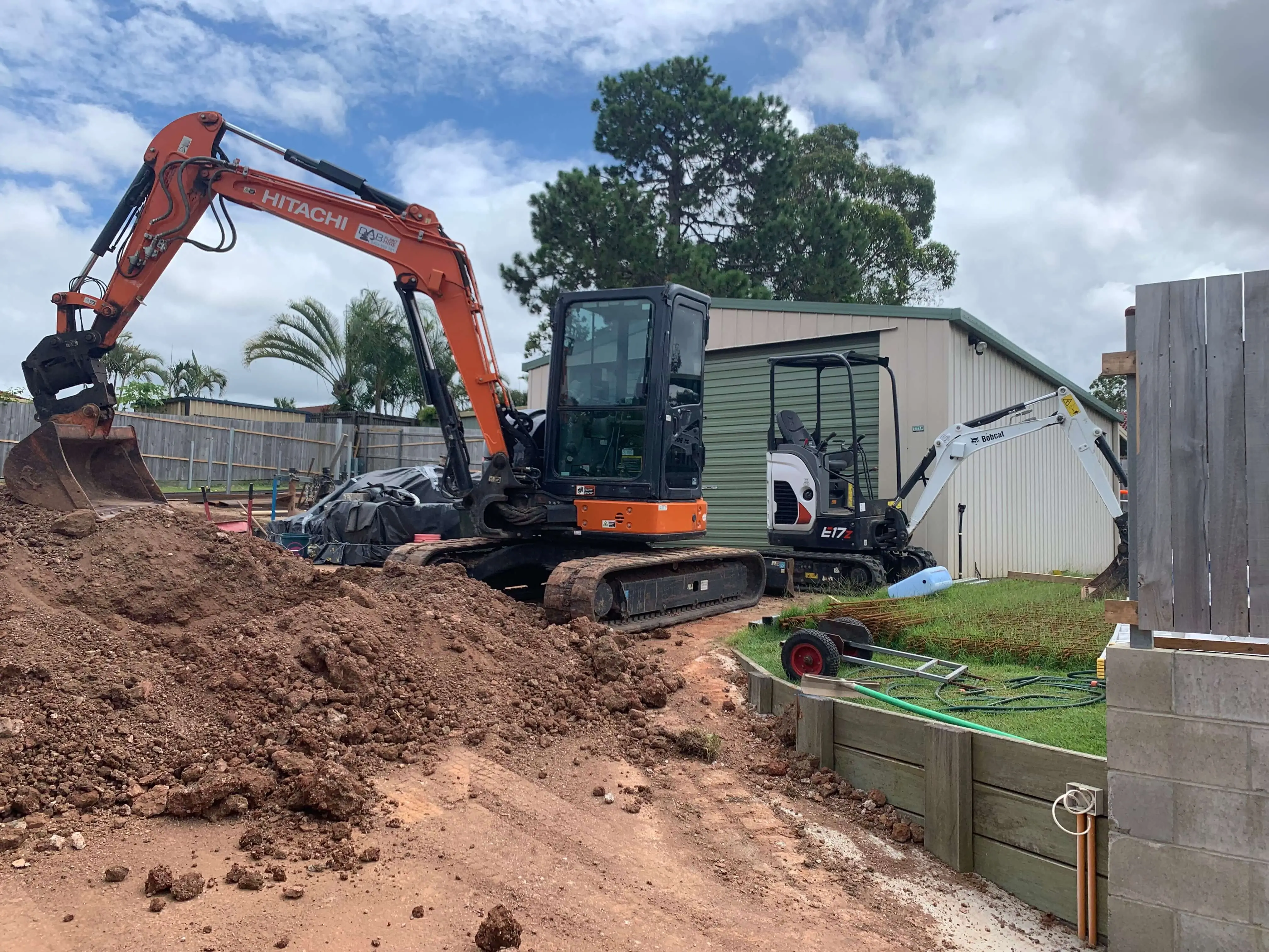 Hitachi and Bobcat excavators cutting into a backyard for new footings