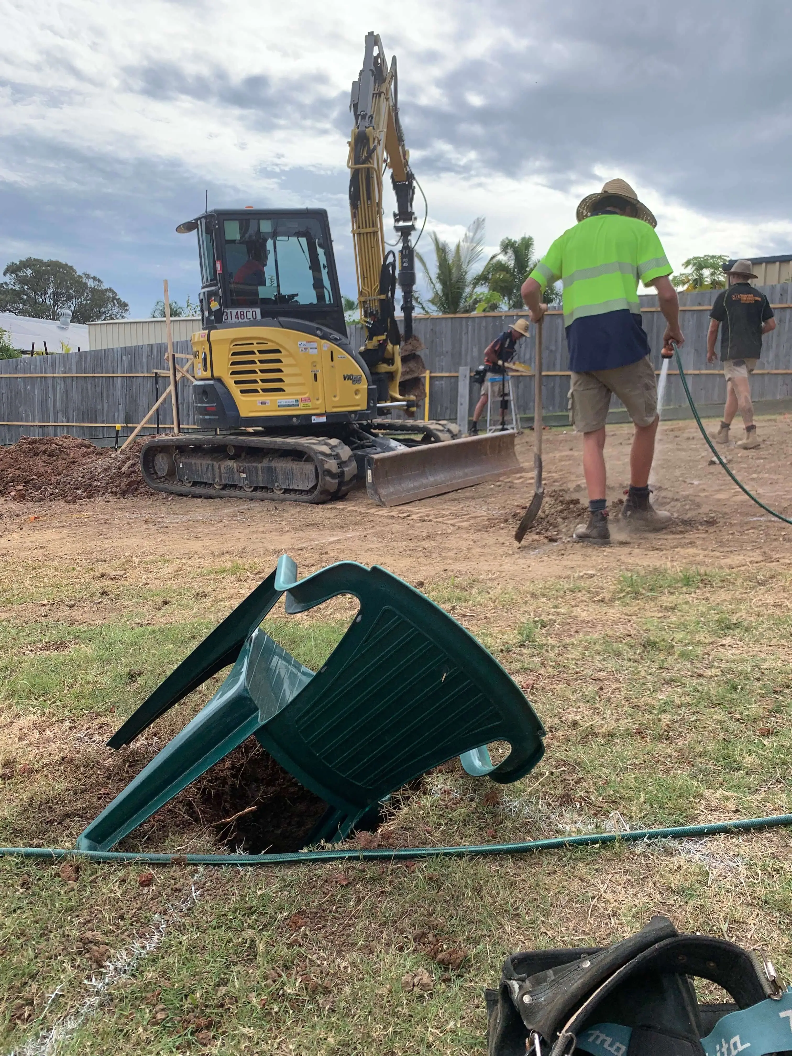 Yanmar excavator auguring post holes while the crew works the string lines