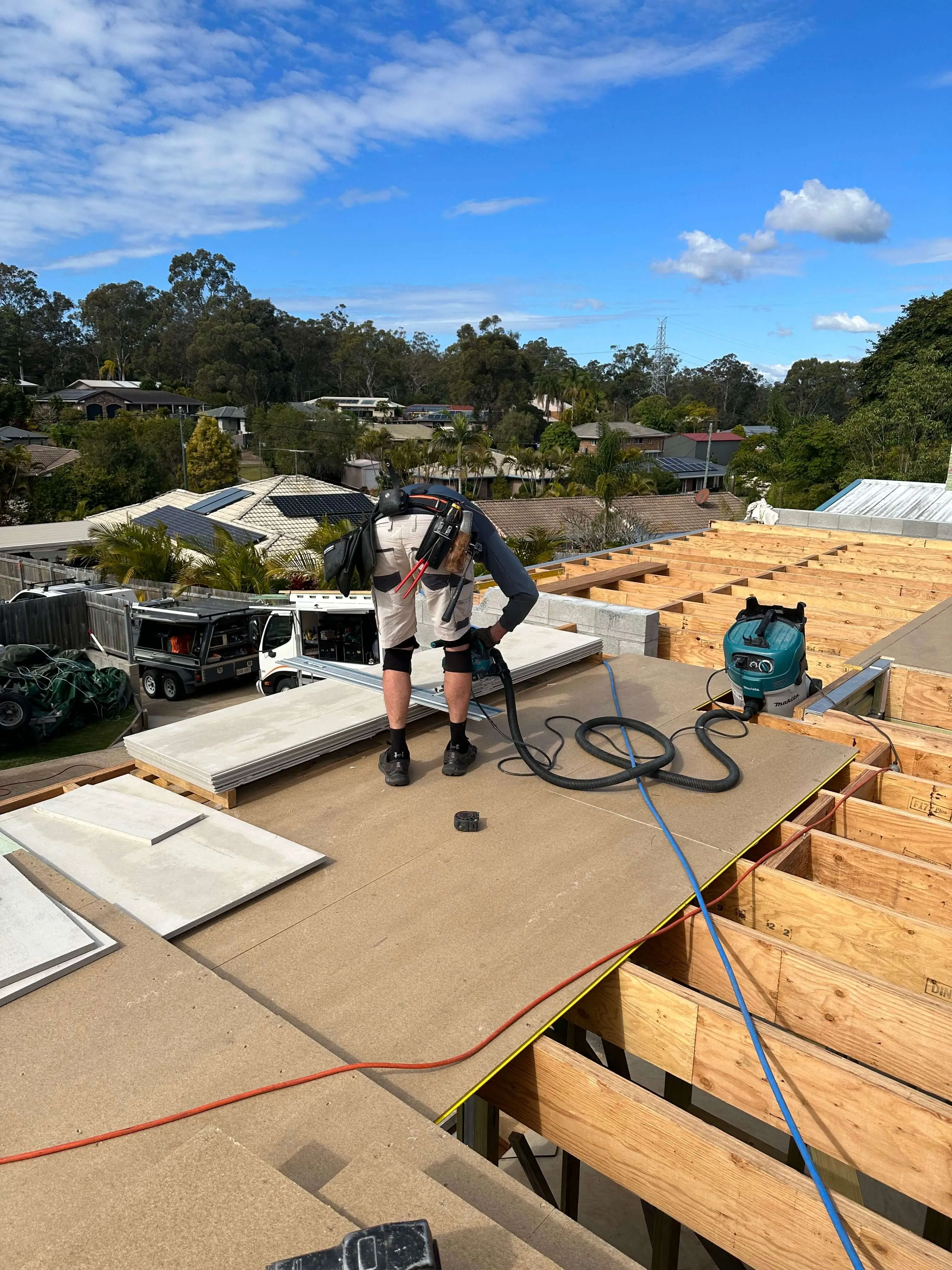Carpenter cutting fibre cement sheet on a new first-floor deck over timber joists