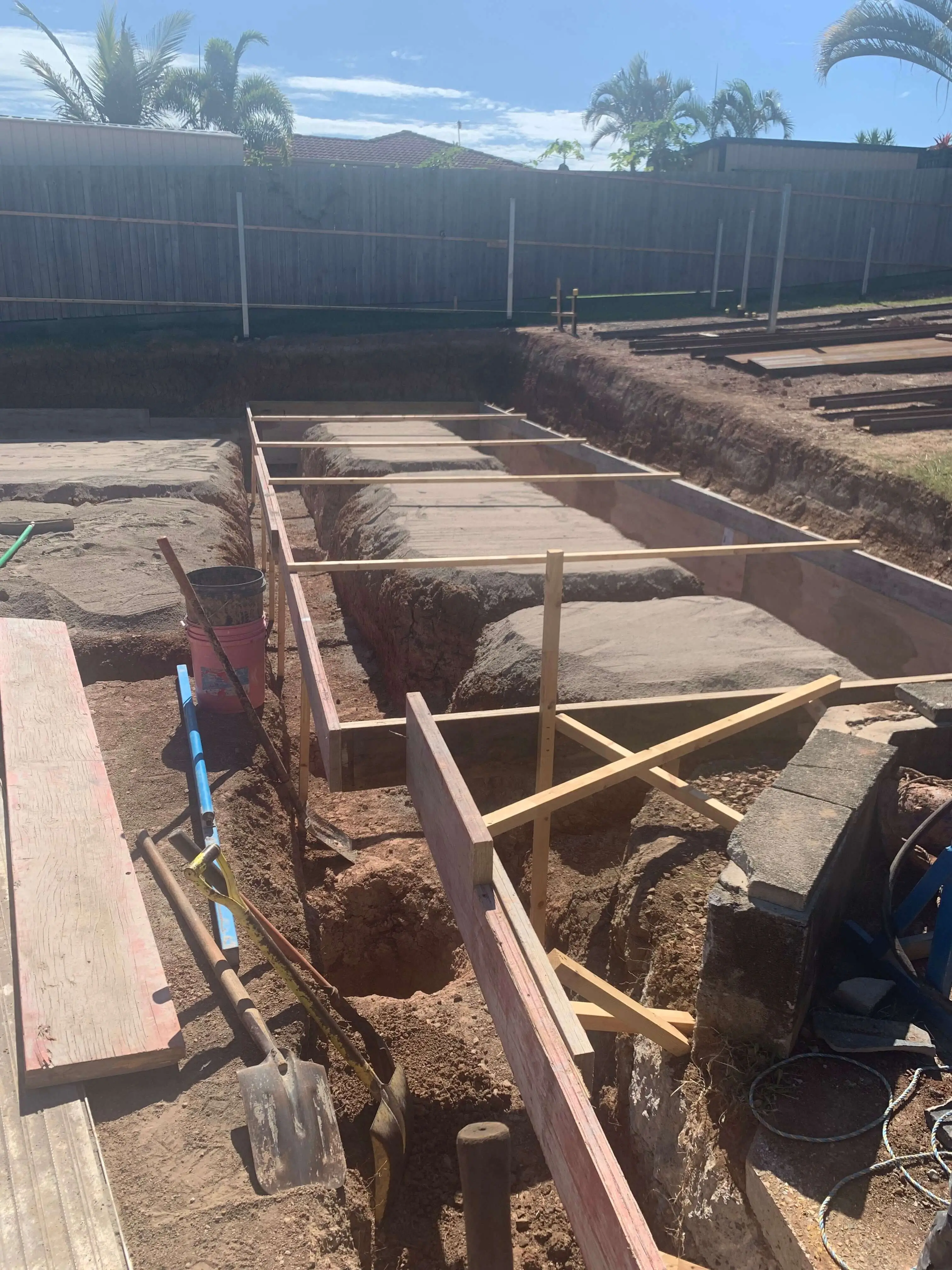 Formwork set into footing trenches across a levelled backyard site