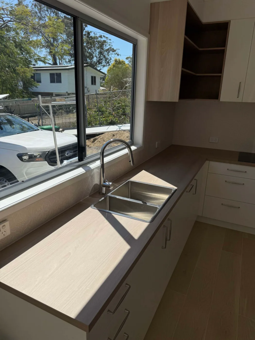 Kitchen sink set under a window with timber-look benchtop, Brisbane renovation