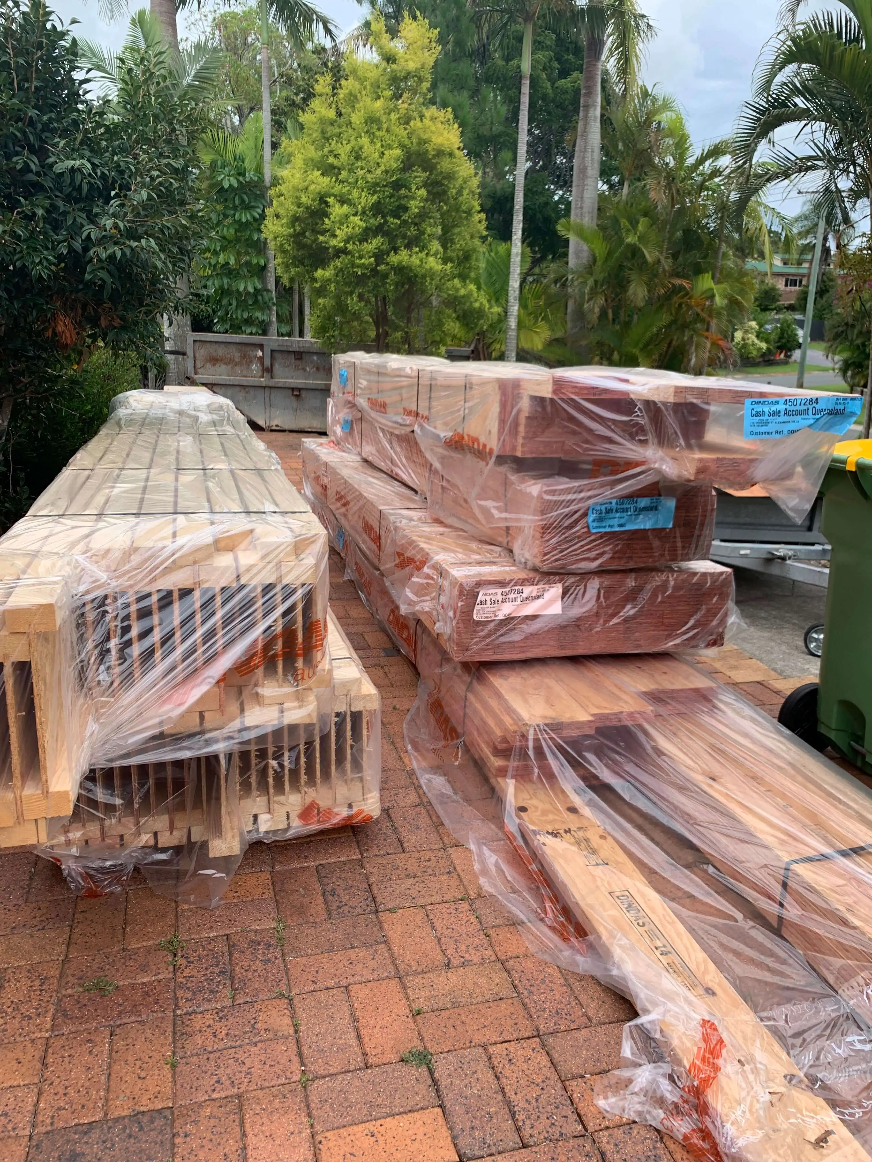 Framing timber and LVL packs wrapped on a paved driveway before a frame start