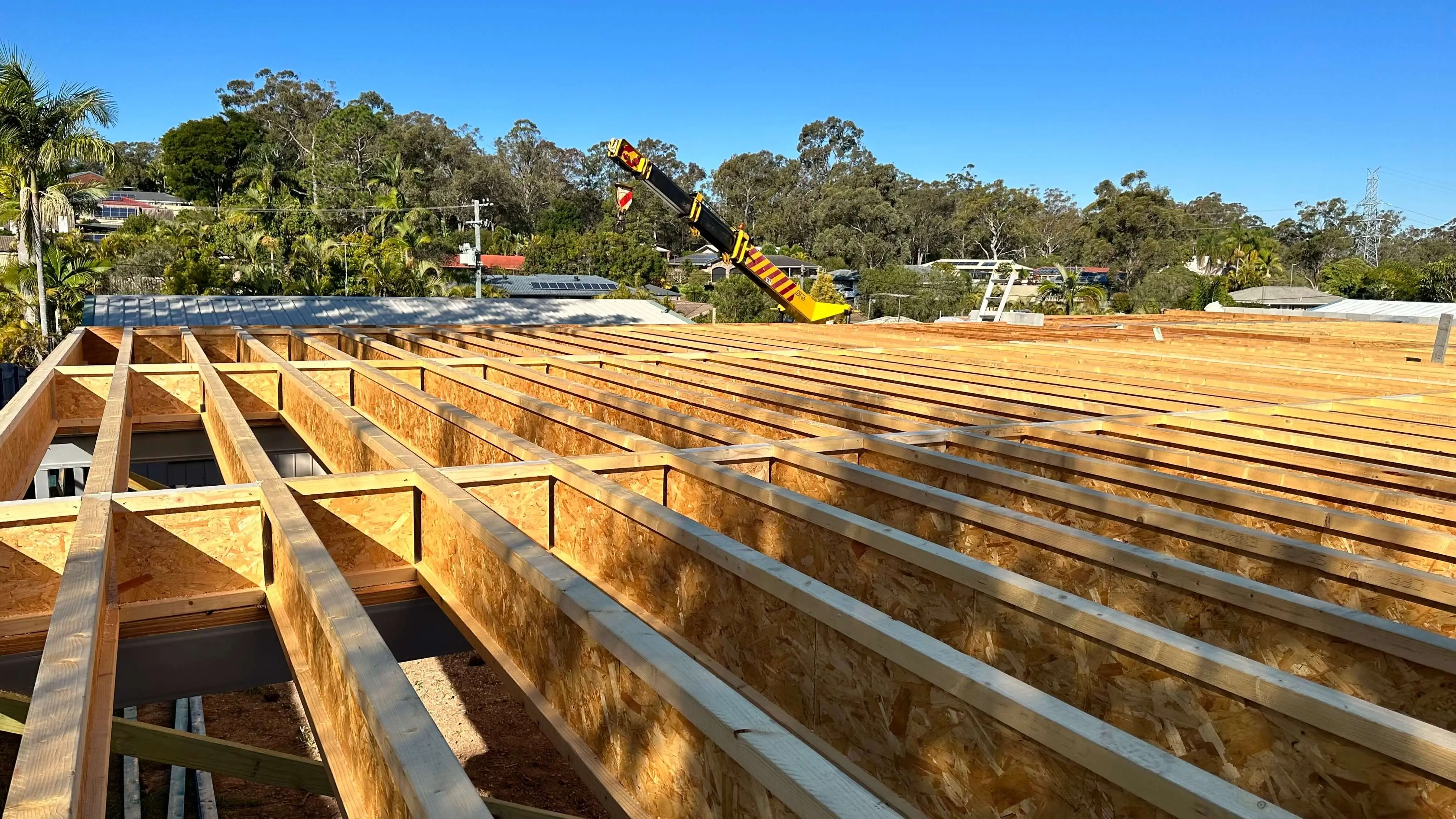 New upper-floor timber joists and framing with a crane boom above, Redlands