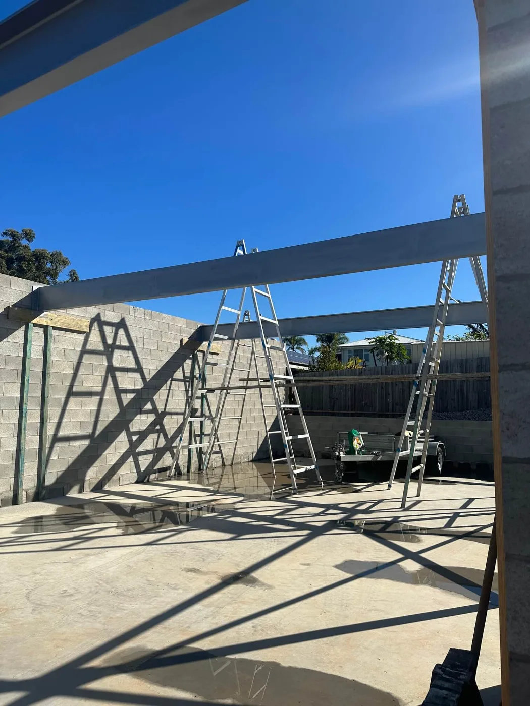 Steel beams being set onto new block walls over a poured slab, Brisbane builder