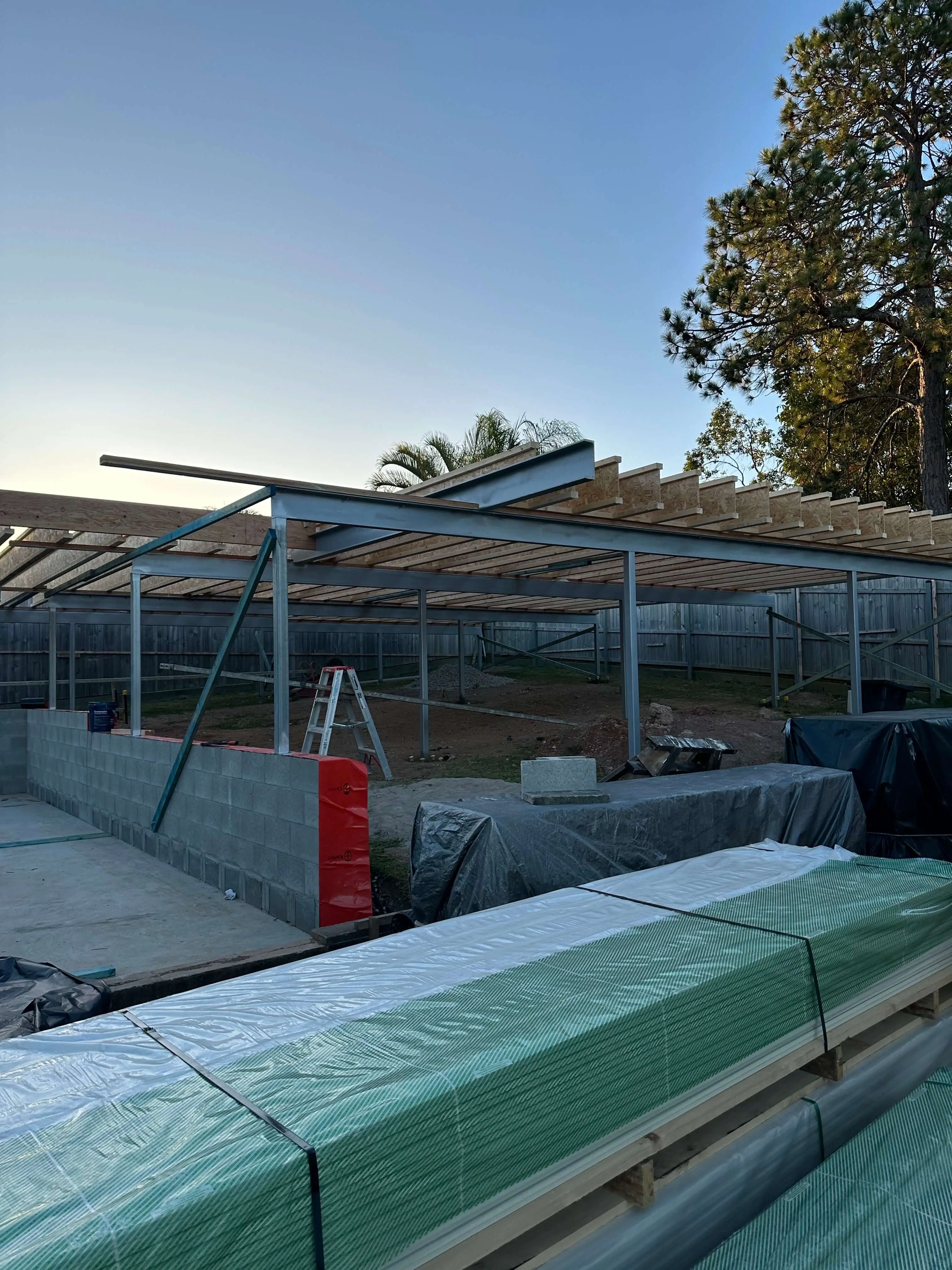 Steel frame with timber rafters over a block retaining wall at dusk